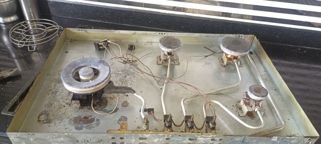 Cleaned gas stove interior tray showing restored metal and polished burners
