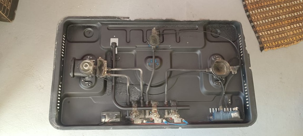 Cleaned gas stove interior tray showing restored metal and polished burners