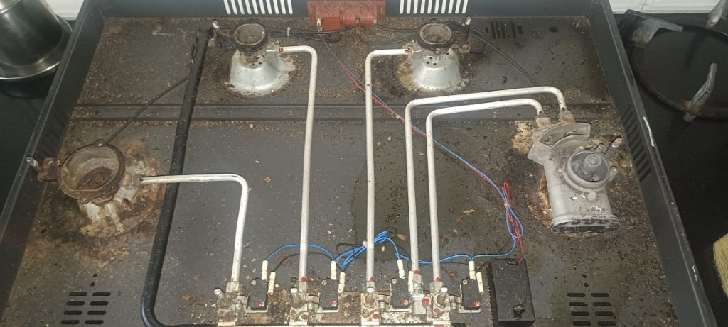 Dirty and greasy gas stove interior tray showing carbon soot residues